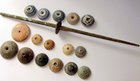 A BRONZE AGE SPINDLE AND A COLLECTION OF SPINDLE WHORLS